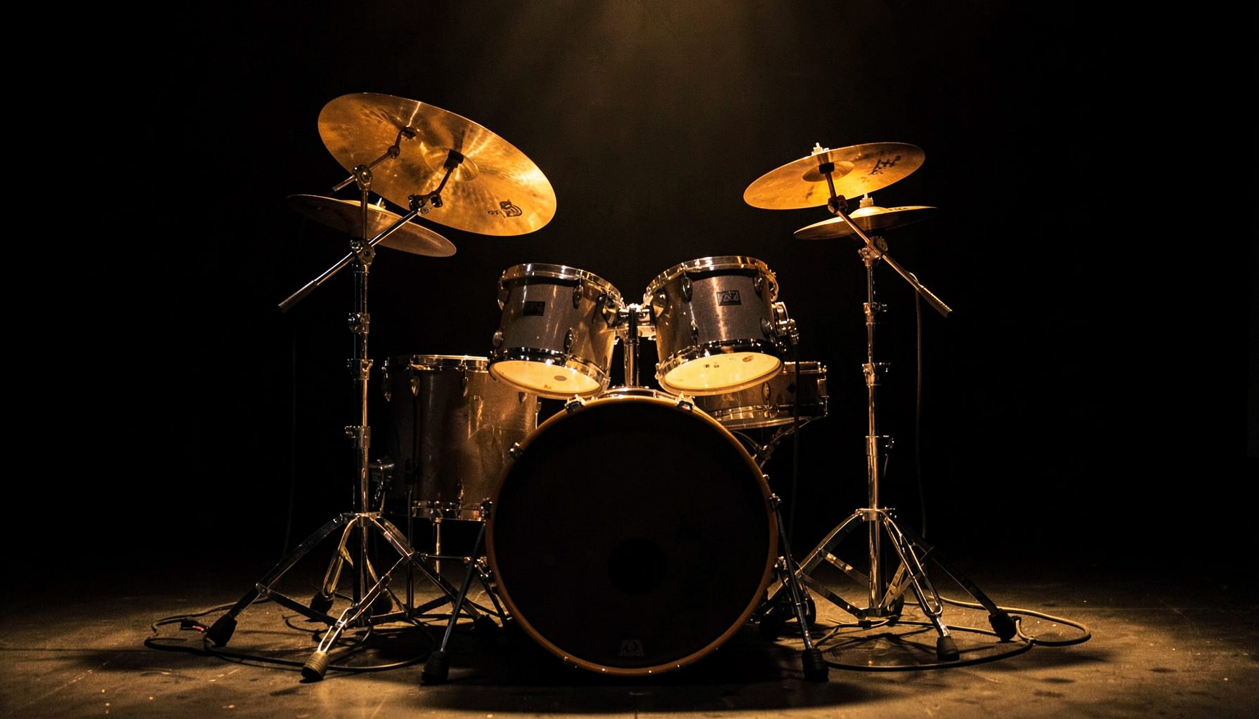 Drum set with cymbals and hardware on a small stage, warm spotlighting against a dark backdrop.