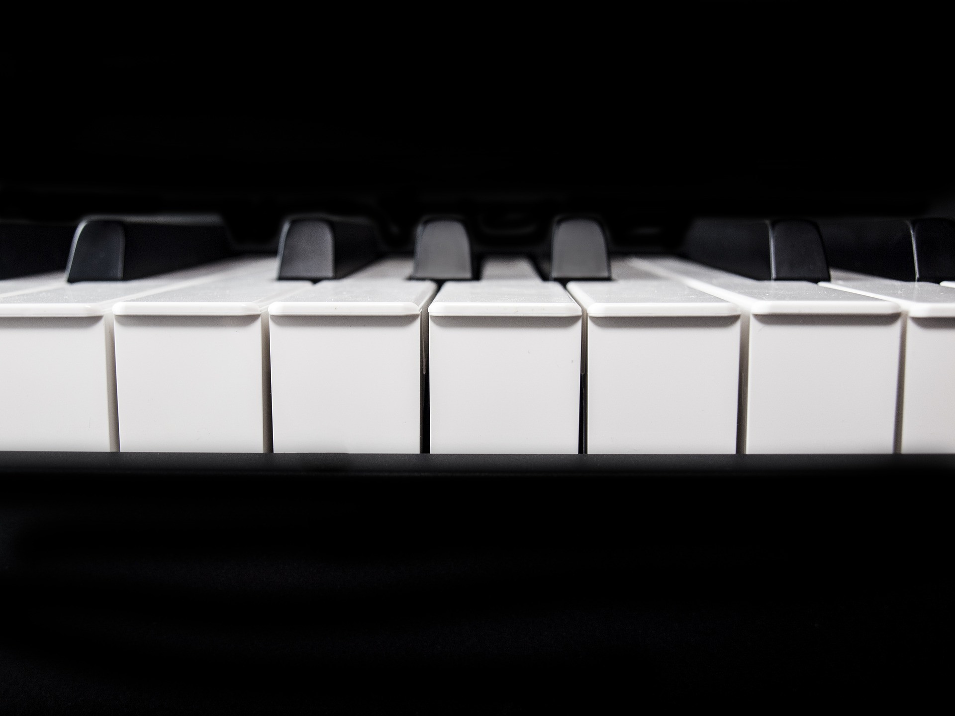 Close-up view of piano keyboard keys, black and white, dramatic lighting against dark background.
